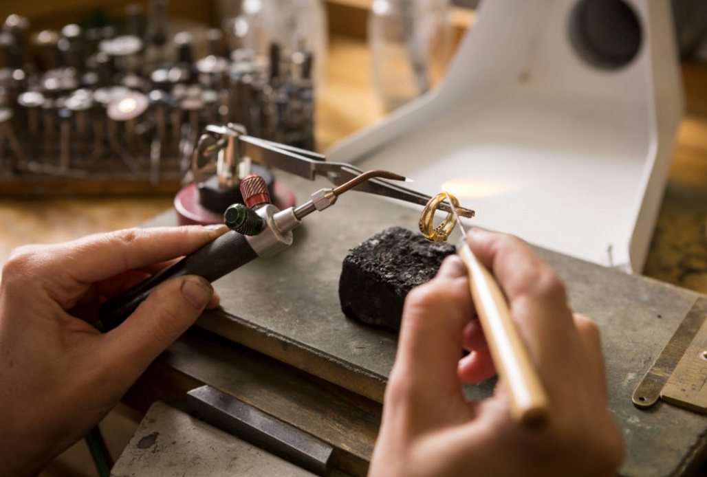A jeweler repairing a ring at the workbench with precision tools